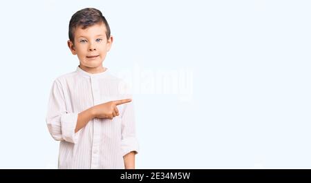 Cute blond kid wearing elegant shirt pointing aside worried and nervous with forefinger, concerned and surprised expression Stock Photo