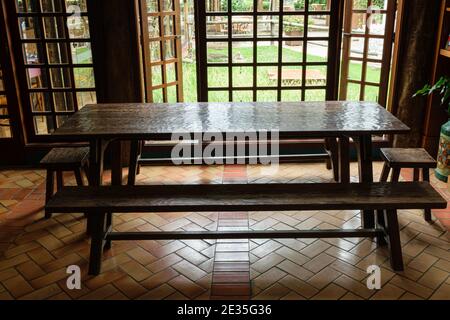 A large old wooden table being lit by the light from the window. Stock Photo