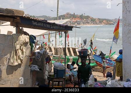 Cape Coast Ghana fishing fleet village. West Africa, Atlantic ocean. Traditional fishing fleet handmade wooden boats, colorful paint. Nets and gear. Stock Photo