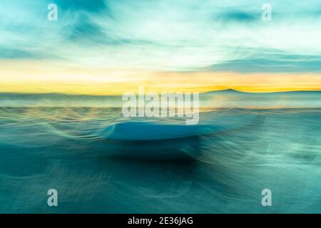 Colorful coastal evocative and  intriguing impressionist style image  with brush stroke painetrly effect of waves in morning light golden and green hu Stock Photo