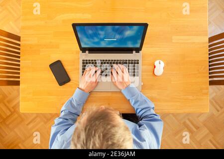Businessman working remote with laptop from home trying to log in - focus on the keyboard Stock Photo
