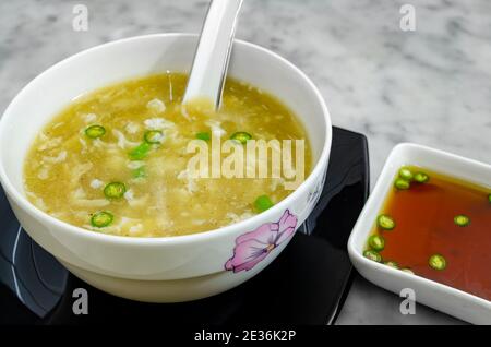 Hot Chicken Clear Soup in a bowl along with spicy chilli sauce to accompany Stock Photo