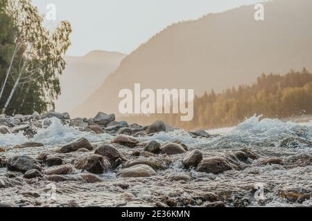 A stormy river among the stones in the Altai Mountains at dawn.