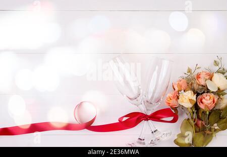 Valentine day concept, wineglass and red ribbon and flower on white wooden table background with bokeh, champaign glass on wood desk, top view, couple Stock Photo