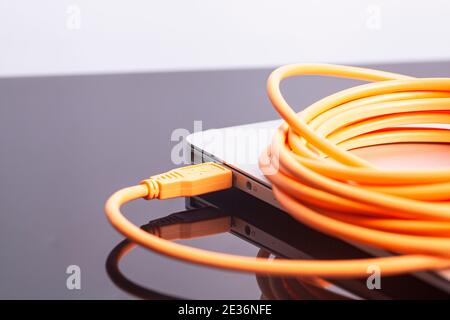 laptop with orange rolled cable. Stock Photo