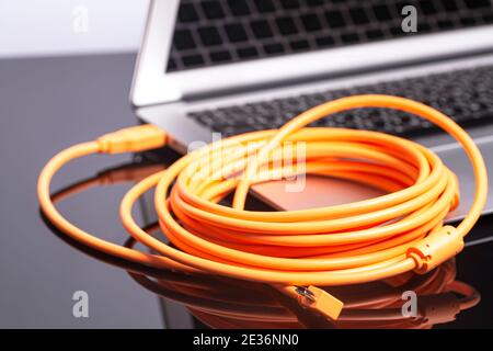 laptop with orange rolled cable. Stock Photo