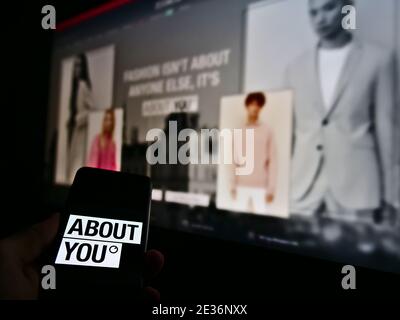 Person holding smartphone with logo of German fashion online retail business About You on display with blurred company website on screen background. Stock Photo