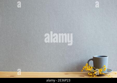 Coffee cup with yellow gypsophila dry flowers on wooden table. gray background Stock Photo