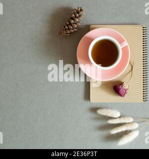 Cup of black tea on notebook with dry plant on gray background. top view, copy space Stock Photo