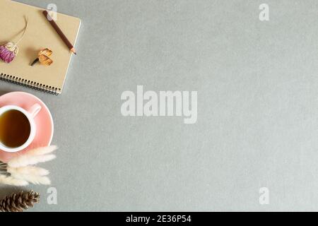 Notebook and cup of black tea with dry plant on gray background. top view, copy space Stock Photo