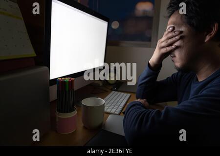 Portrait of Asia Businessman sitting and working hard on the table with front of computer desktop in work place at late with serious action, Work hard Stock Photo