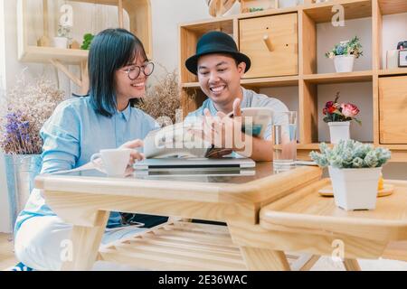 Asian couple reading the magazine over the desk which have technology laptopn in modern workplace or co-working space, freelance and lifestyle or leis Stock Photo