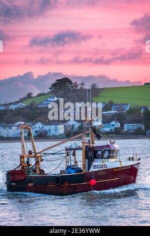 Appledore, North Devon, England. Sunday 17th January 2021. UK Weather. After a cold night, the little fishing boat Relentless returns to Bideford under a colourful dawn sky, passing the quay at Appledore in North Devon. Credit: Terry Mathews/Alamy Live News Stock Photo