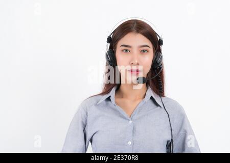 Portrait of happy smiling female customer support phone operator short hair, wearing a white shirt with headset standing one side holding the earphone Stock Photo