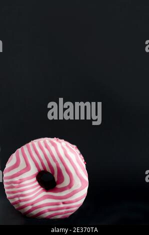 Donuts with bright pink frosting stand on black background with copy space Stock Photo