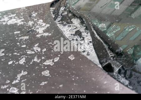 Thawed and crushed ice on the hood of the car near the wipers and windshield close-up Stock Photo