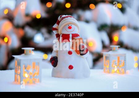 Atmospheric outdoor Christmas decoration with snowman, lanterns, snow and fairy lights on Christmas tree Stock Photo