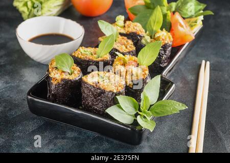 Raw rolls with vegetable filling wrapped in seaweed with basil and soy sauce on a black background Stock Photo