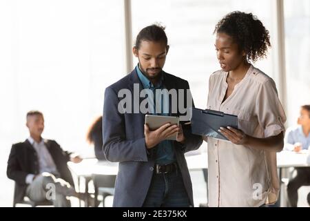Multiracial diverse employees brainstorm together using tablet Stock Photo