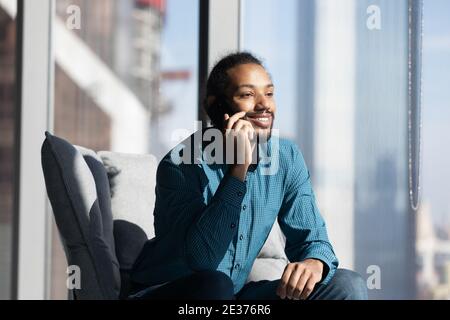 Smiling ethnic man use cellphone talking with client Stock Photo