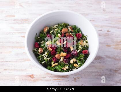 Warm kale salad with brown rice, dried cranberries and nuts on a light background. Delicious healthy diet food Stock Photo