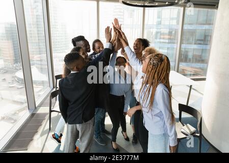 Overjoyed multiracial employees give high five at meeting Stock Photo