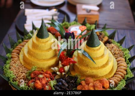 tumpeng, traditional Javanese food, complete food with side dishes. Celebration food in java. Yellow rice with side dishes Stock Photo