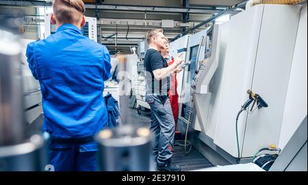 Factory floor with workers at lathe machine Stock Photo