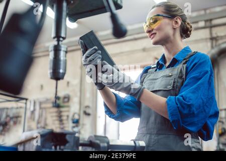 Woman in metal workshop checking workpiece Stock Photo
