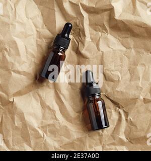 Amber glass dropper bottles on kraft paper. Natural serums top view. Stock Photo