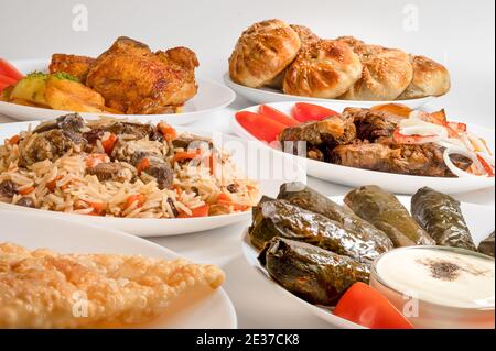 Kazan kabob, Plov, Dolma and fried chicken. Uzbek Main dishes on white plates. Stock Photo