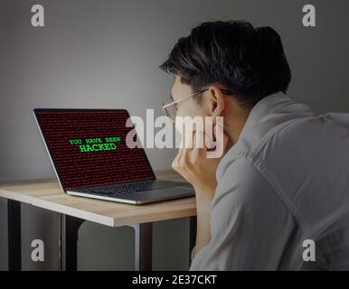 You have been hacked on computer laptop screen watching by asian man Stock Photo