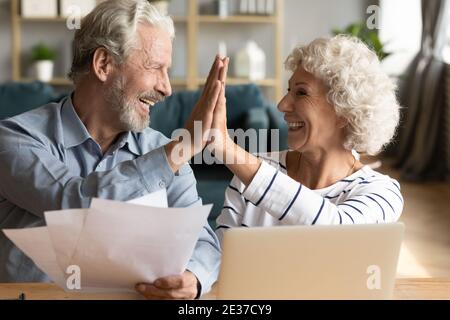 Smiling old hoary man giving high five to mature wife. Stock Photo