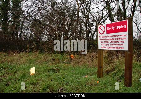 No fly tipping sign on a road side lay by, with some littering evident. Stock Photo