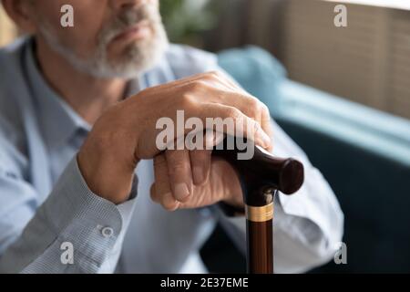 Thoughtful middle aged disabled grandfather resting on sofa. Stock Photo