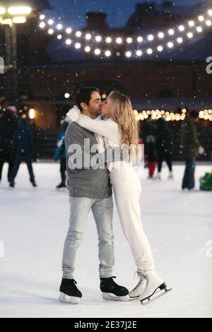 Happy couple of lovers having fun hugging an kissing at ice skating rink outdoor. St. Valentines Day Stock Photo