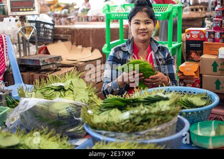Portrait of a local Burmese woman with thanaka selling paan chewing tobacco with betel vine leaves and areca nut at a market near Yangon Stock Photo