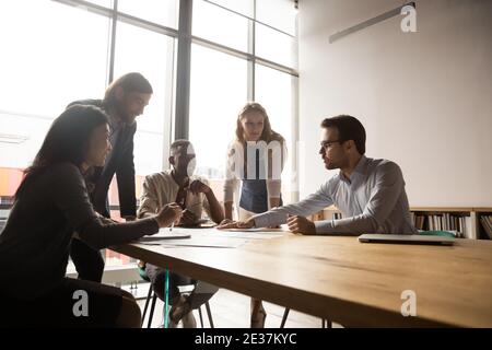 Happy mature and young multiracial employees discussing working issues. Stock Photo