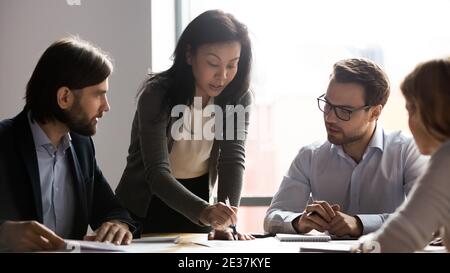 Serious middle aged korean female team leader holding briefing meeting. Stock Photo