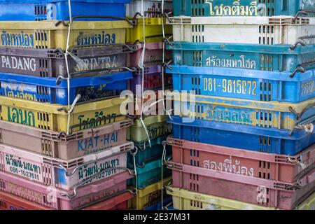 Colorful industrial plastic baskets with text and numbers on them stacked at a local market in Myanmar Stock Photo