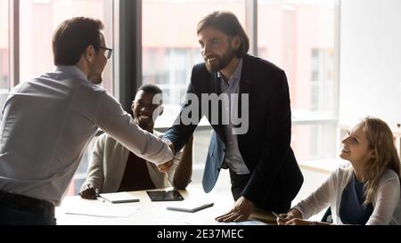 Happy two caucasian businessmen in formal wear shaking hands. Stock Photo