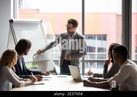 Skilled 30s caucasian leader in eyeglasses coaching employees. Stock Photo