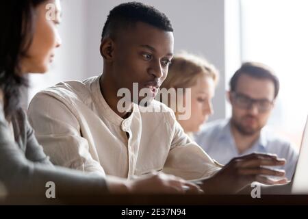 Focused young african employee working on computer with old colleague. Stock Photo
