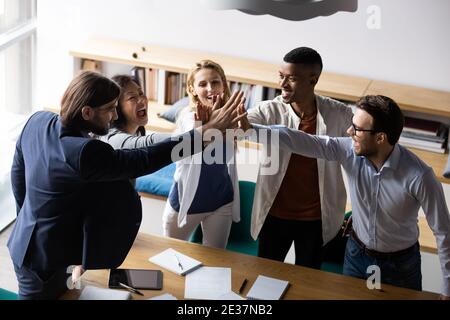 Laughing mixed race teammates giving high five to each other. Stock Photo