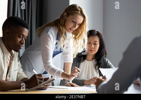 Serious millennial female team leader presenting research results to colleagues. Stock Photo