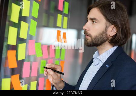 Focused young male project manager analyzing working processes. Stock Photo