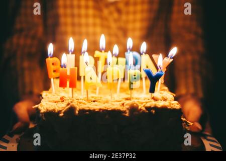 Woman holding a birthday cake with burning candles in hands. Stock Photo