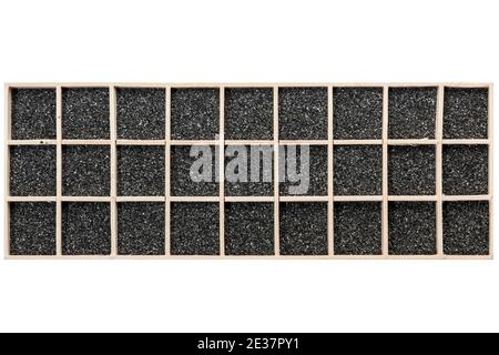 Black decorative sand distributed in a rectangular wooden box with square compartments. Stock Photo