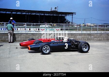 Jackie Stewart parks his BRM H-16 (slimmer version, type P115) Formula 1 car behind the pits next to Chris Amon's V-12 Ferrari, during practise for the 1967 British Grand Prix, at Silverstone on 14th July. Stock Photo