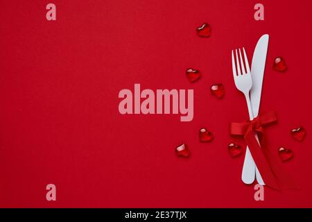 Valentines day background or concept with empty white plate, small heart-shaped plate with small hearts inside and whiteware on scarlet or red backgro Stock Photo